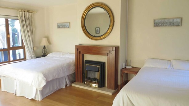 A hotel room with two beds, a fireplace, a mirror, and a window with curtains. - Fantastic bungalow in quiet rural setting close to Enniscorthy town. Sleeps 6. (Enniscorthy)
