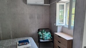 Un dormitorio con cama, una silla, cómoda y ventana.