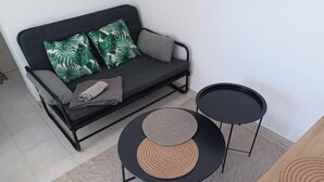 Una sala de estar moderna con un sofá, dos mesitas redondas y un tapete tejido.