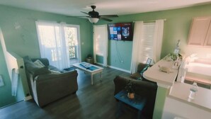 Una sala de estar con sofá, mesa de centro y televisor montado en la pared.