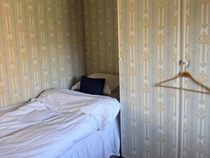 A single bed with a white bedspread, a dark blue pillow, and a wooden hanger on the wall. - 5 Star Holiday Home in Enhorna (Enhorna)
