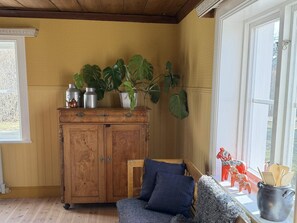 Ein Zimmer mit einem Holzkabinett, einem blauen Sofa und einem Fenster mit Dekoration.