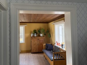 A room with a wooden bench, a cabinet with plants, and a window. - 5 Star Holiday Home in Enhorna (Enhorna)