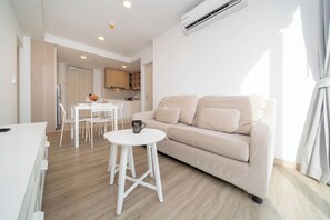 Ein modernes Wohnzimmer mit einem beigen Sofa, einem weißen Couchtisch und einem Essbereich mit einem weißen Tisch und Stühlen.