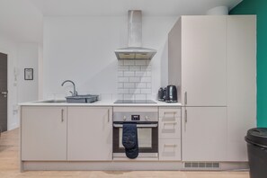 A modern kitchen with a built-in oven, a stainless steel range hood, and a dishwasher. - Marvelous 2-bedroom apartment in charming Birmingham city center (Birmingham)