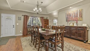 Uma sala de jantar com uma mesa de madeira, cadeiras, um candelabro e um quadro na parede.