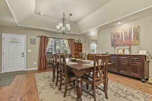 A dining room with a wooden table, chairs, a chandelier, and a painting on the wall. - Family-Friendly Mountain Getaway with Deck, Grill & Fireplace (Woodland Park)