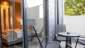 A room with a bed, a glass partition, a chair, and a table.