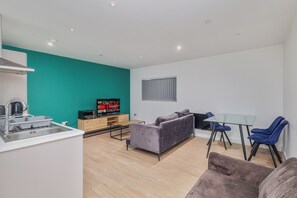 Una sala de estar moderna con un sofá, una mesa de vidrio y un televisor.