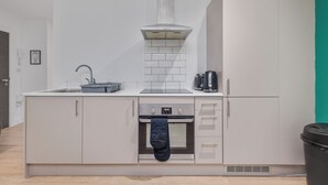 A modern kitchen with a built-in oven, a stainless steel range hood, and a dishwasher. - Enjoyable 2-bedroom apartment in beautiful Birmingham city center (Birmingham)
