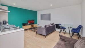 A modern living room with a sofa, a glass table, and a TV. - Enjoyable 2-bedroom apartment in beautiful Birmingham city center (Birmingham)