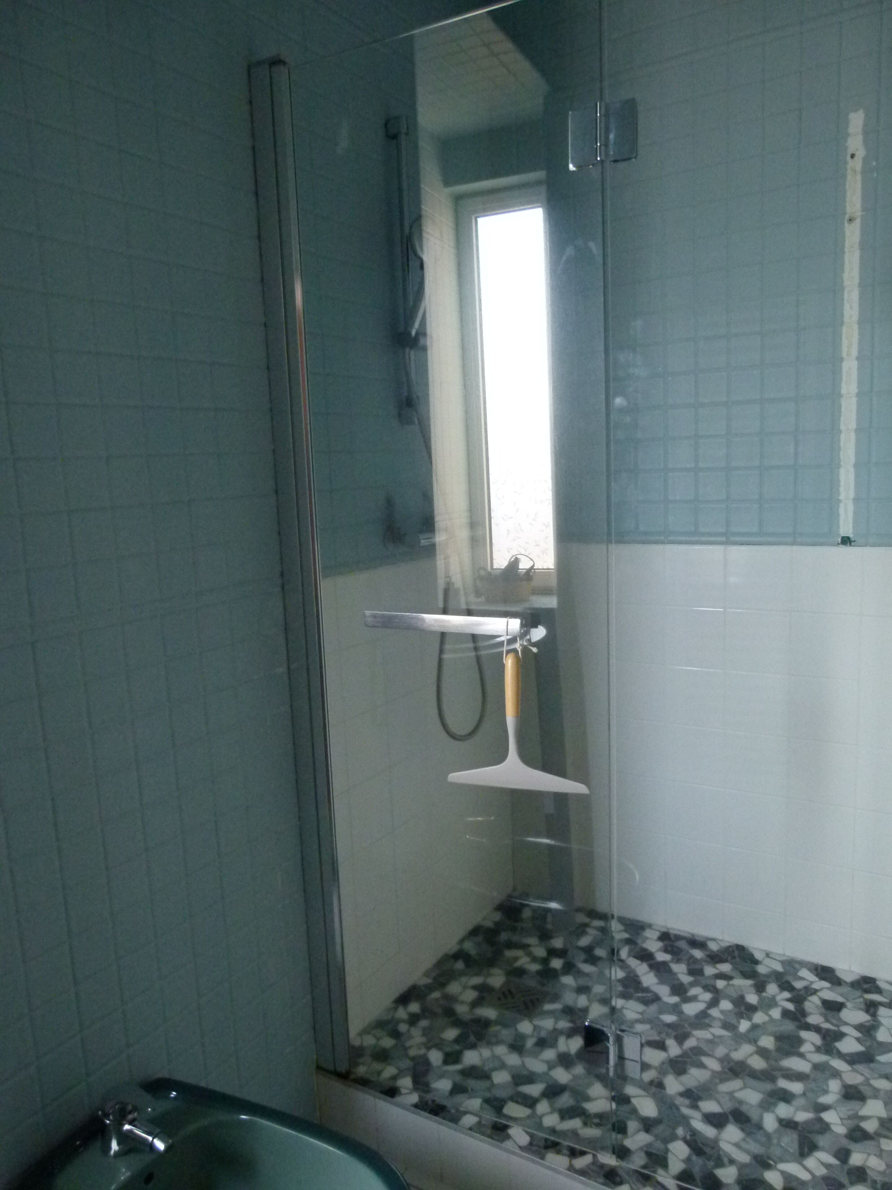 A bathroom with a shower, a sink, and a tiled floor.