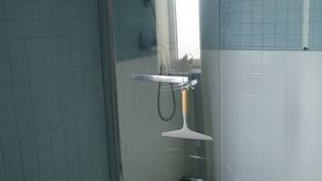 A bathroom with a shower, a sink, and a tiled floor.