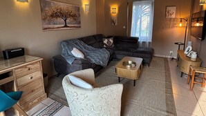 A living room with a sofa, armchair, coffee table, and a desk with a chair. - Charming house 3 suites/terrace/garden 6 persons (Moulins)