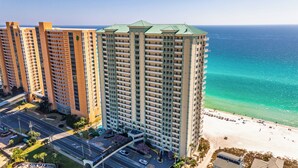 Un hotel di grandi dimensioni con diverse altezze, vista sulla spiaggia e un'area di parcheggio.