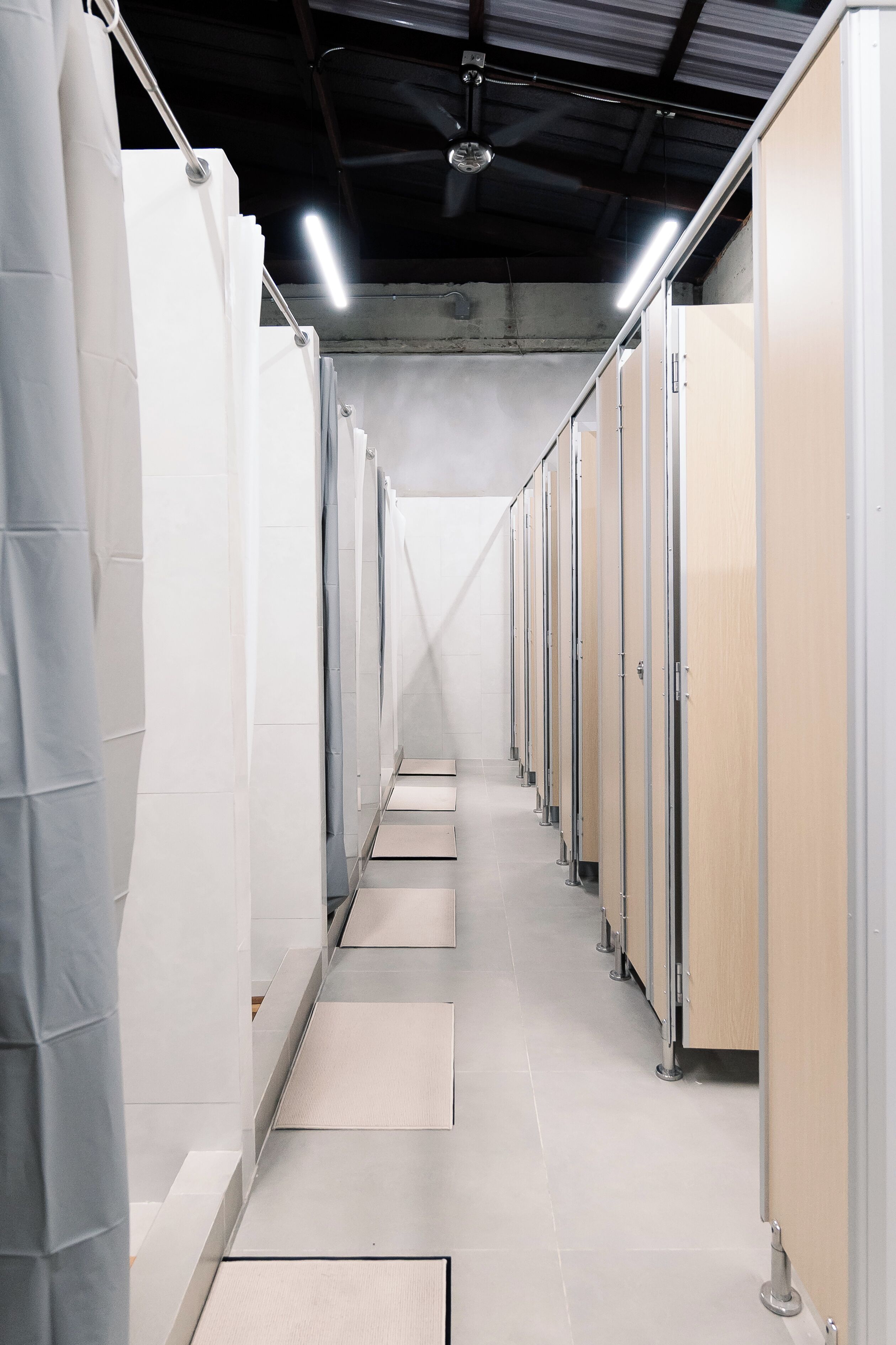 Un couloir bordé de chambres individuelles, chacune dotée d’une porte et d’un petit seuil menant à l’entrée.