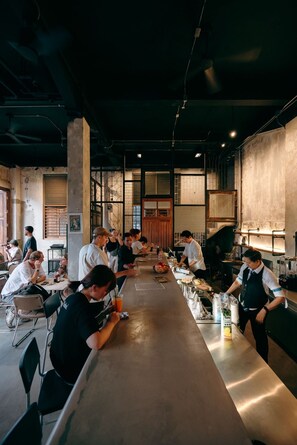 A restaurant interior with a long counter, bar area, and seating for patrons. - Kosin House (Bangkok)
