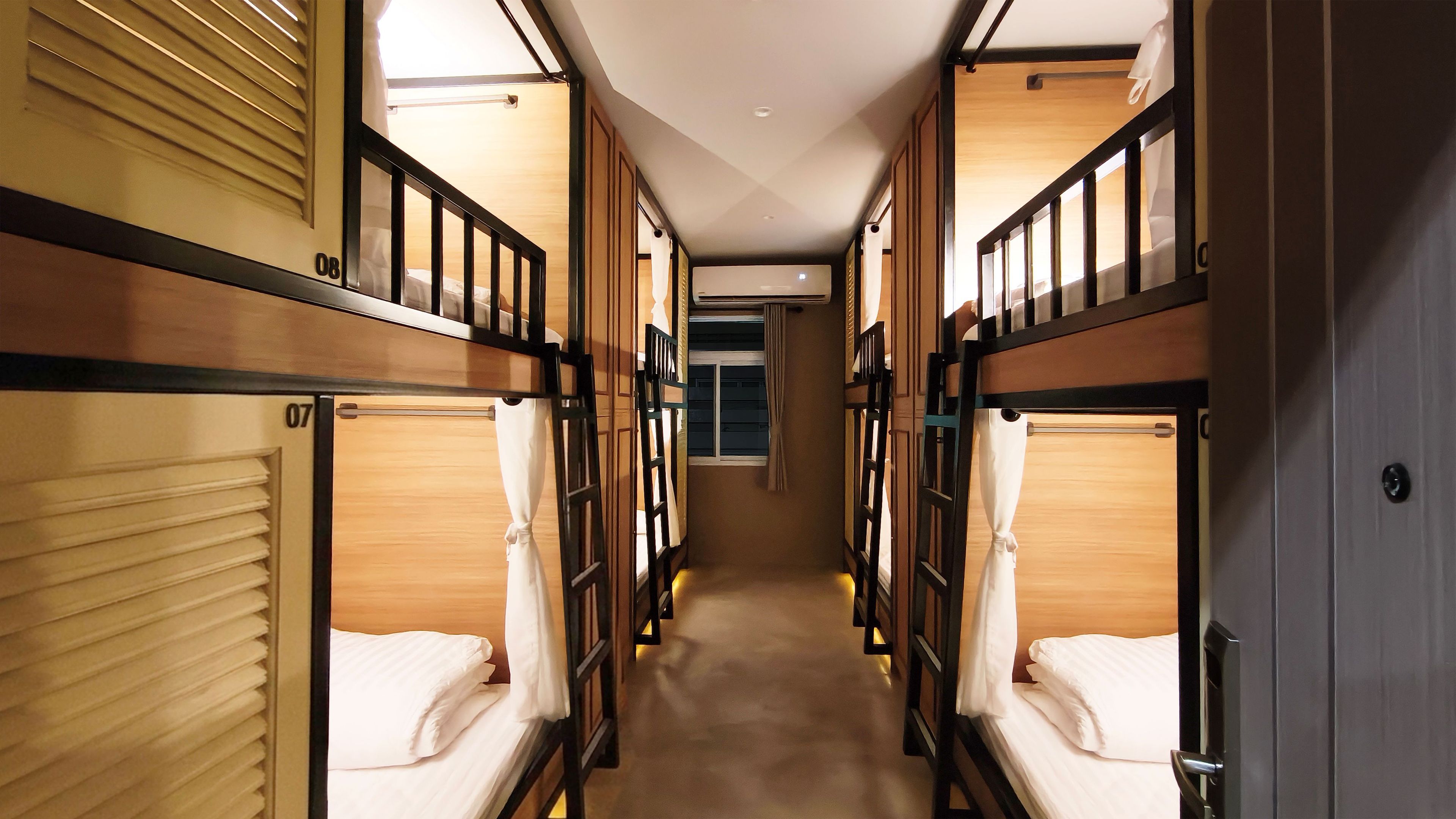 A corridor with bunk beds, each with a window and curtains.