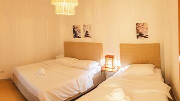 Habitación de hotel con dos camas, una lámpara colgante y decoración en la pared.