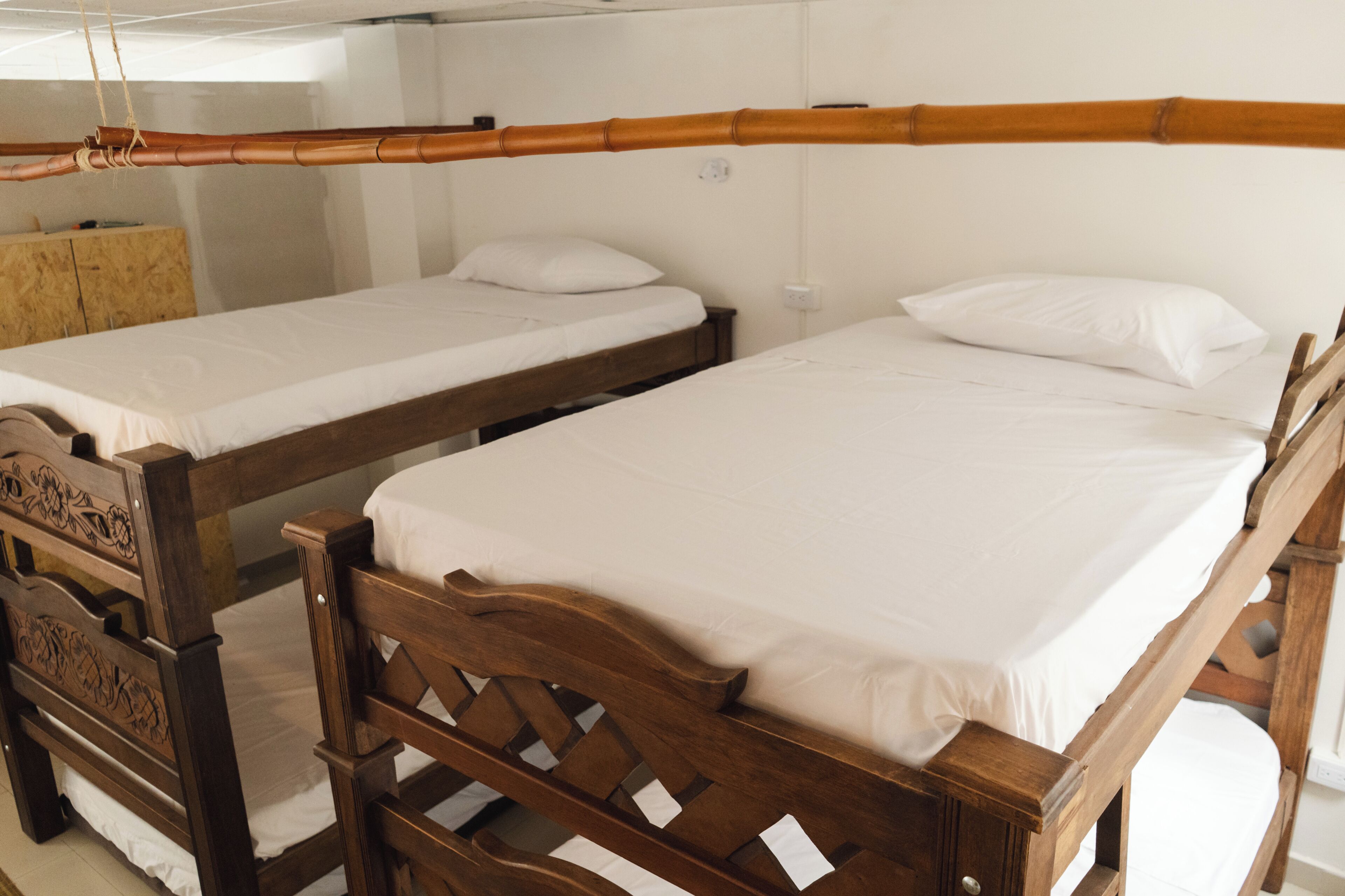 Dos camas de madera con sábanas blancas en una habitación con paredes blancas.