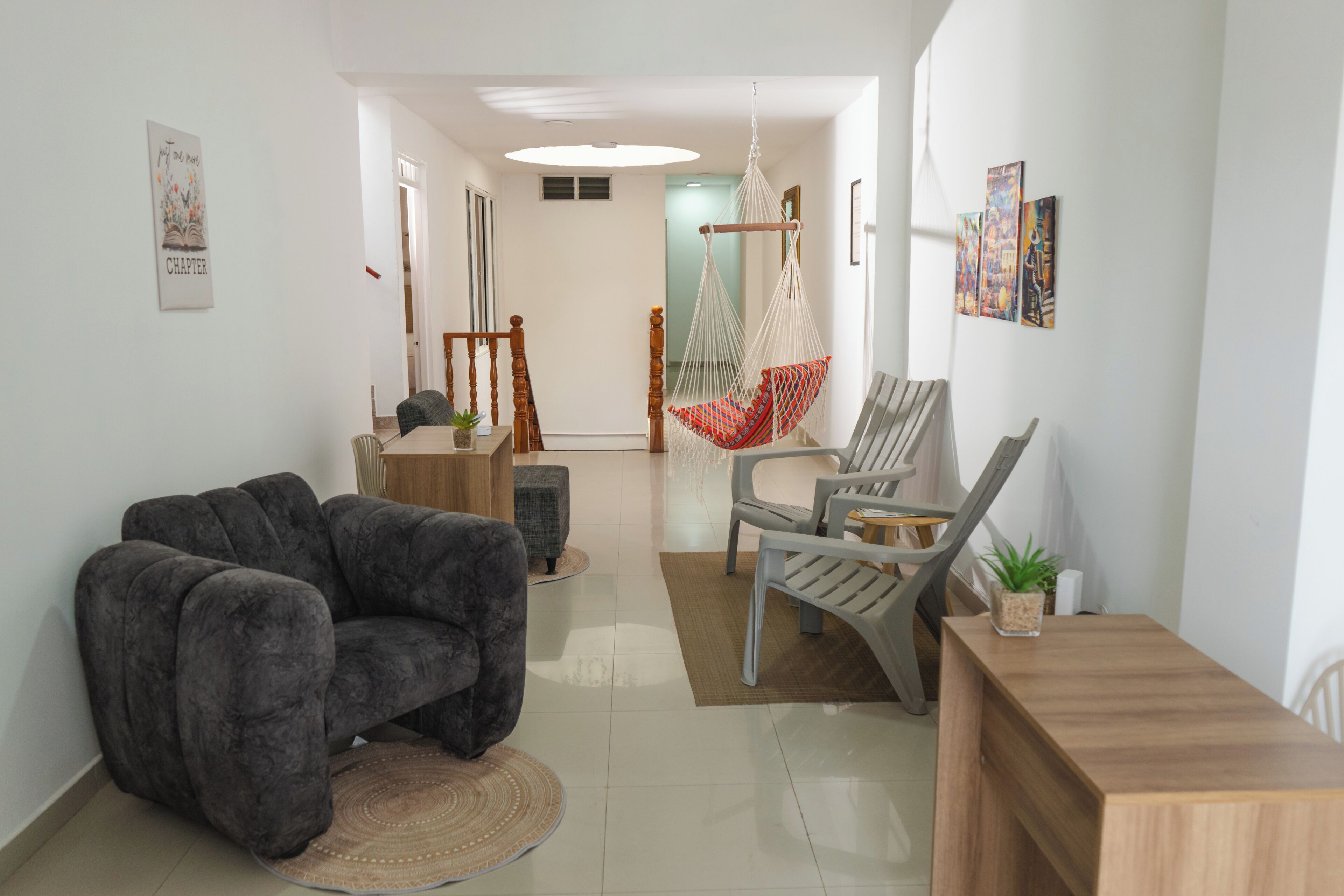 Una sala de estar moderna con un sofá, sillas, una silla colgante y una mesa de madera.