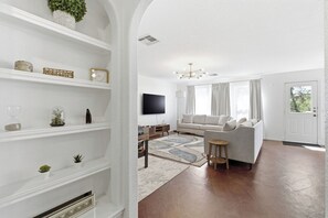 A living room with a sofa, TV, and decorative shelves. - Spacious 5-bedroom house in tranquil Austin with hot tub (Austin)