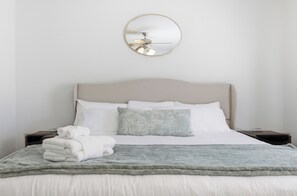 A neatly made bed with white linens, a grey throw blanket, and a stack of folded towels. - Spacious 5-bedroom house in tranquil Austin with hot tub (Austin)