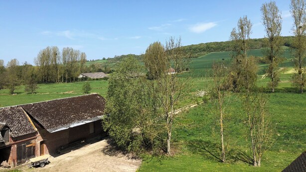 A rural landscape with a brick building, a dirt path, and green fields. - Gîte le Moulin Fontaine (Saint-Martin-le-Gaillard)