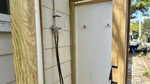 A wooden structure with a shower, a door, and a window.
