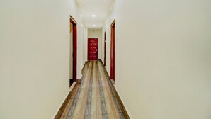 Un pasillo con suelo de baldosas y una puerta roja al final.