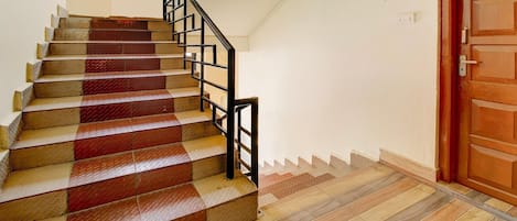 Una escalera con peldaños que alternan rojo y beige, que conduce a una puerta de madera.