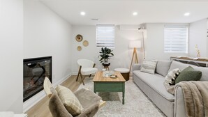 En moderne stue med pejs, sofa, sofabord og fjernsyn.
