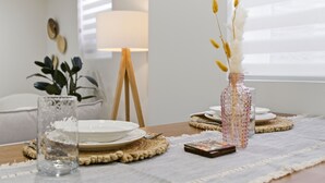 Et spisebord dækket med tallerkener, en vase med pampas og en glasvase med sand.