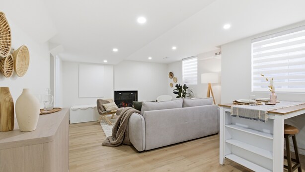 En moderne stue med sofa, sofabord, fjernsyn og spiseområde med bord og stole.