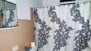 Et badeværelse med vask, toilet og bruseforhæng.
