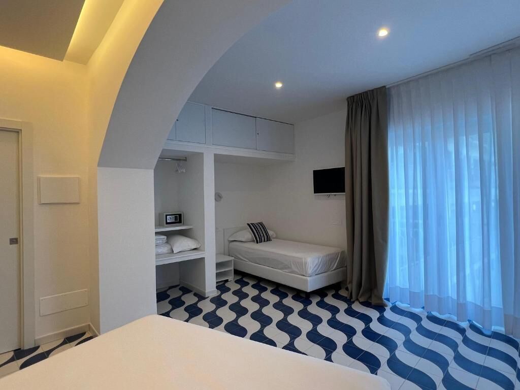 A hotel room with a bed, a TV, a wardrobe, and a window with curtains.