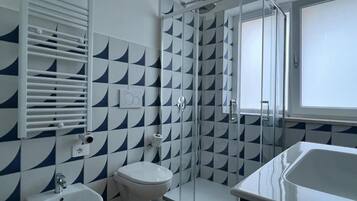 A bathroom with a bidet, toilet, and shower.