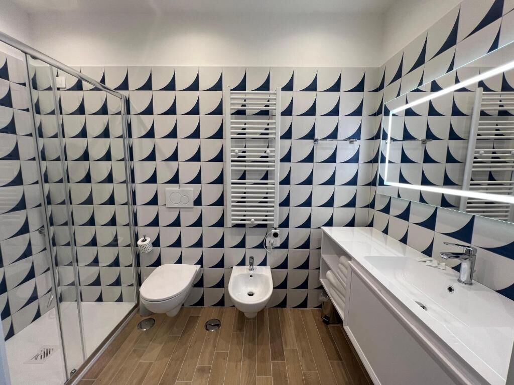 Un bagno moderno con un motivo a scacchi in piastrelle, un bidet, un water e un grande specchio.