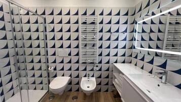 Un bagno moderno con un motivo a scacchi in piastrelle, un bidet, un water e un grande specchio.