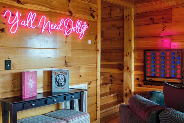 A wooden interior with a neon sign, a book titled 'Dolly Parton,' and a dartboard. - Bear’s Eye View - Sleeps 12, Hot Tub, Game Room & Mountain Views (Sevierville)