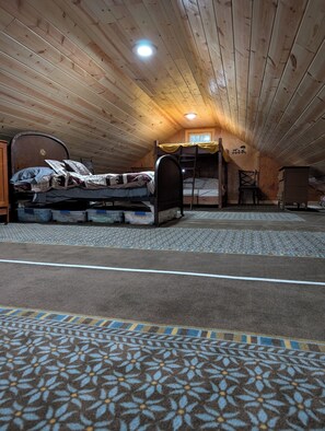 Un dormitori tipus loft amb un llit superposat, una escala, una cadira i una commode.