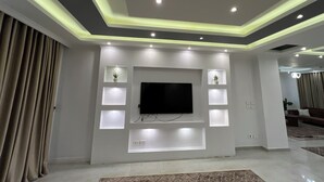 A modern living room with a flat-screen TV, recessed lighting, and built-in shelving. - ELITE Comfort 3BR Apartment New Cairo   (New Cairo)