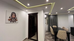 A conference room with a dark wooden door, a painting on the wall, and a table with chairs. - ELITE Comfort 3BR Apartment New Cairo   (New Cairo)