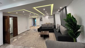 A modern living room with a sofa, coffee table, and a large plant. - ELITE Comfort 3BR Apartment New Cairo   (New Cairo)
