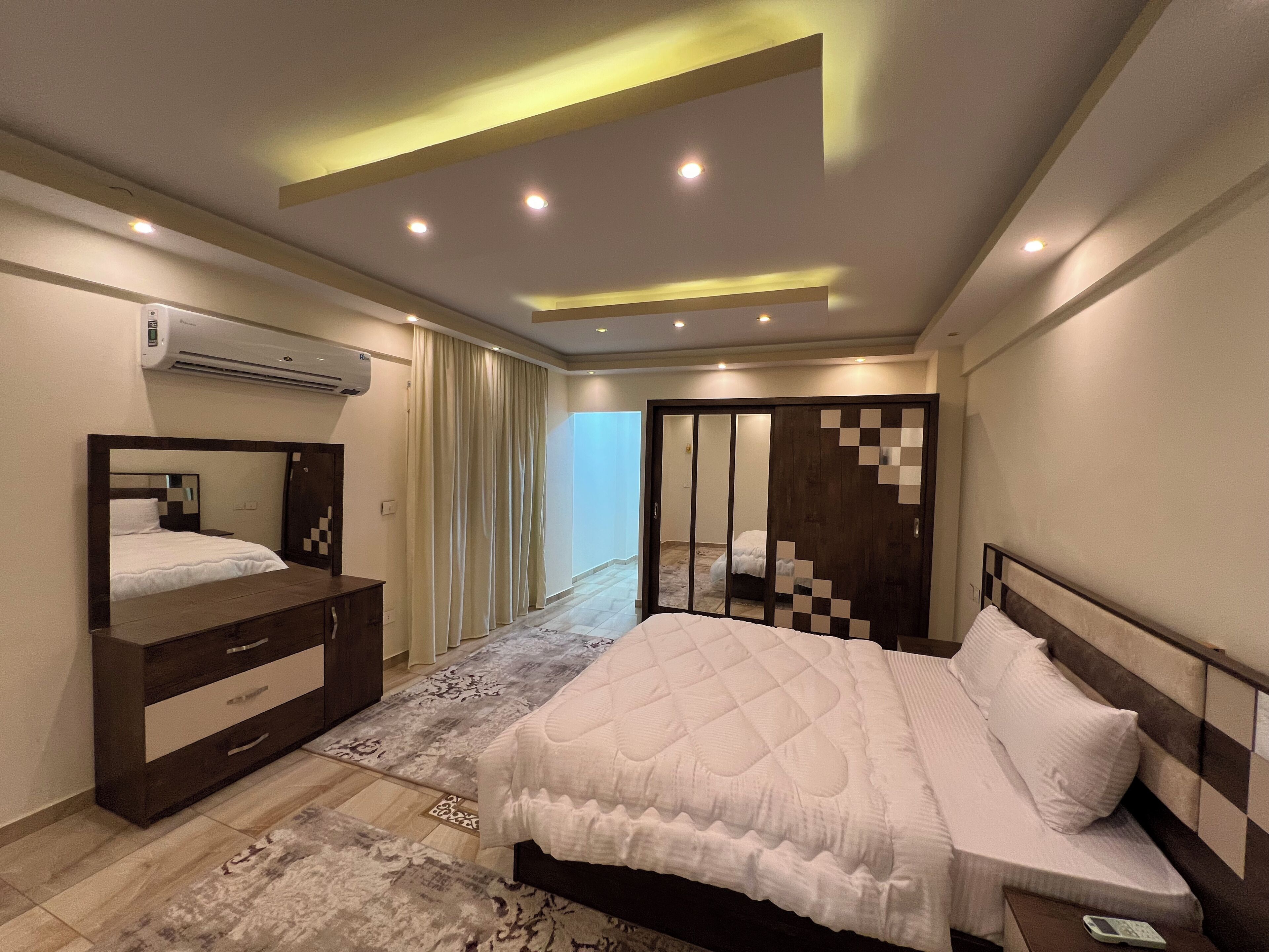 Un dormitorio moderno con cama, cómoda, espejo y armario corredero.