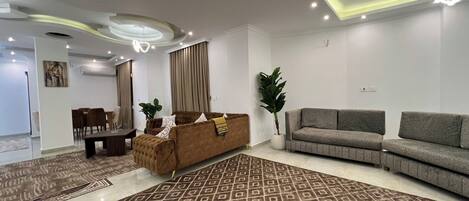 Una sala moderna con alfombra estampada, sofás, zona de comedor e iluminación empotrada en el techo.