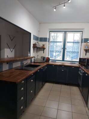 Una cocina moderna con armarios oscuros, encimera de madera, un fregadero, un tostador y una ventana con vistas.