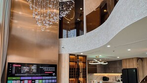 A modern interior with a large TV, a chandelier, and a kitchen area. - Duplex Penthouse - River Bridge View in City Center, Thu Thiem, Ho Chi Minh City (Thành phố Hồ Chí Minh)