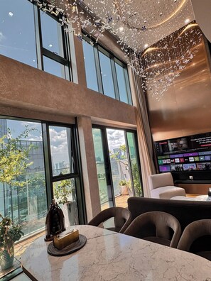 A modern interior with large windows, a flat-screen TV, and a dining area with a marble table. - Duplex Penthouse - River Bridge View in City Center, Thu Thiem, Ho Chi Minh City (Thành phố Hồ Chí Minh)