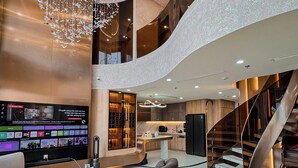 A modern interior with a TV displaying content, a staircase, and a seating area. - Duplex Penthouse - River Bridge View in City Center, Thu Thiem, Ho Chi Minh City (Thành phố Hồ Chí Minh)